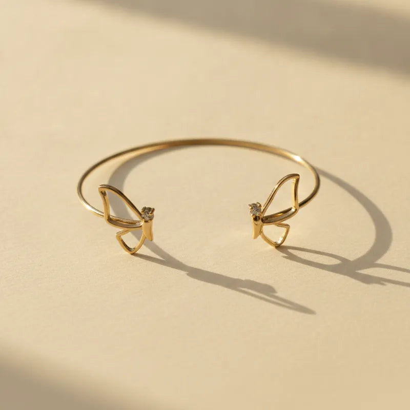 Gold plated adjustable butterfly cuff bracelet with gold tone finish featuring delicate butterfly designs and gemstone accents