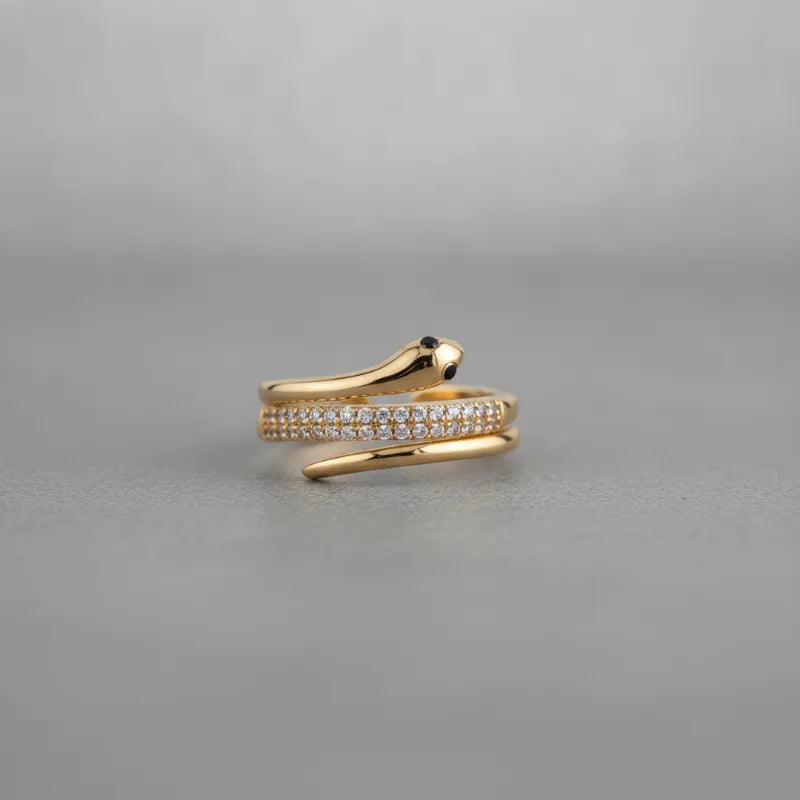 Elegant coiled snake wrap gold ring with pave-set clear stones and a black eye detail on the snake body