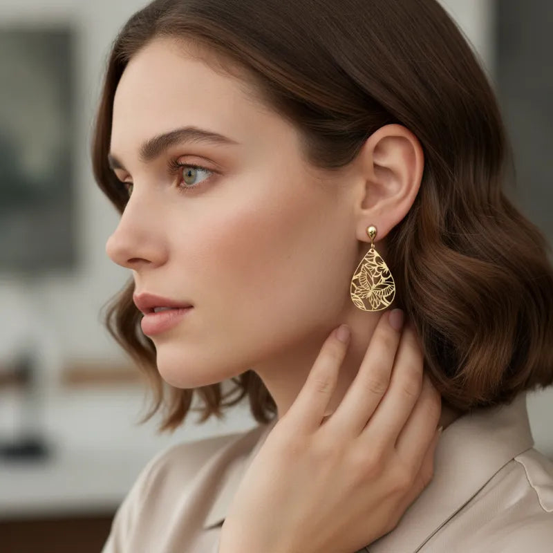 Delicate gold lacecut teardrop earrings featuring intricate butterfly filigree and leaf pattern in gold material