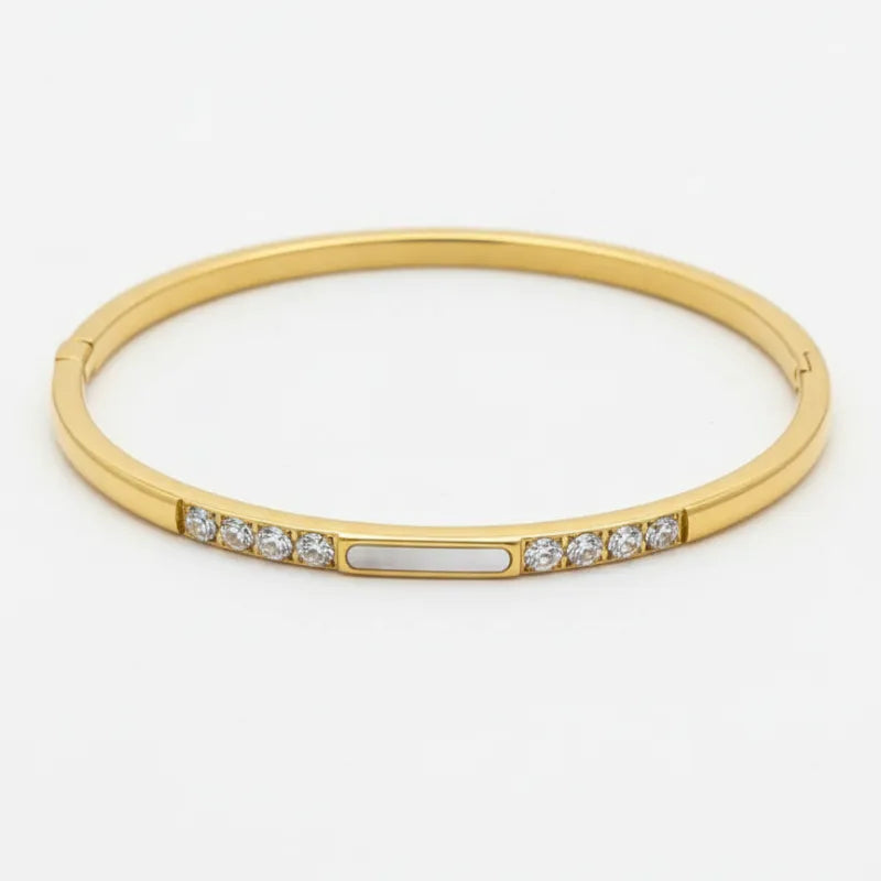 Gold-toned crystal bangle with clear crystals and central mother of pearl accent for women’s boho chic clothing shop daisy