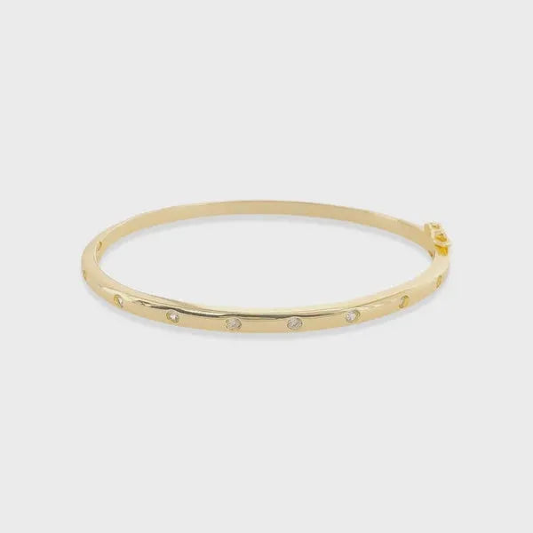 Thin polished cubic zirconia bangle in gold tone adorned with evenly spaced clear cubic zirconia gemstones