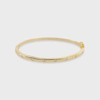 Thin polished cubic zirconia bangle in gold tone adorned with evenly spaced clear cubic zirconia gemstones