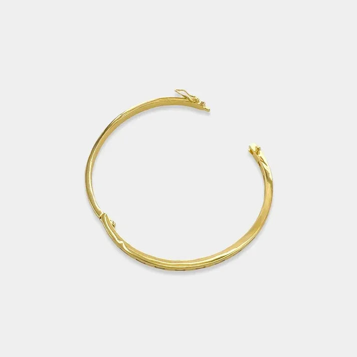 Gold-toned cubic zirconia bangle with a textured twisted design and hinged closure for elegant wear
