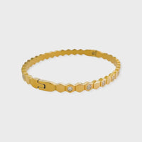 Gold-toned water resistant bangle with a zigzagged hexagonal design and embedded clear stones