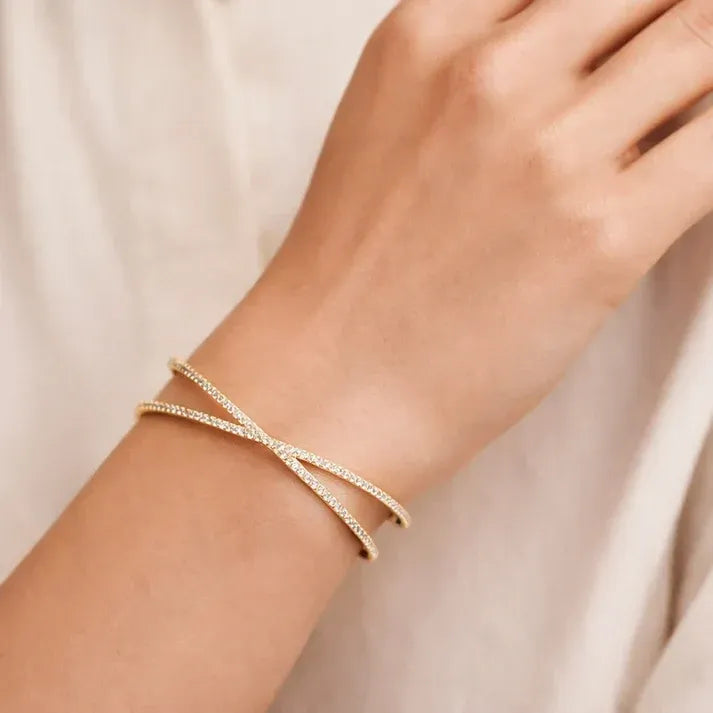 Gold-toned crisscross shape open cuff bracelet with delicate pavé stones and an elegant open cuff design