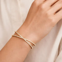 Gold-toned crisscross shape open cuff bracelet with delicate pavé stones and an elegant open cuff design