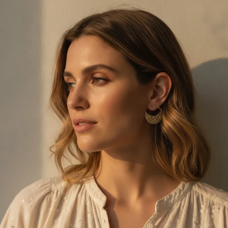 Gold-tone botanical cutout hoop earrings featuring intricate lace-like patterns for chic statement jewelry