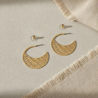 Gold-tone crescent-shaped hoop earrings with intricate botanical cutout design for chic statement jewelry