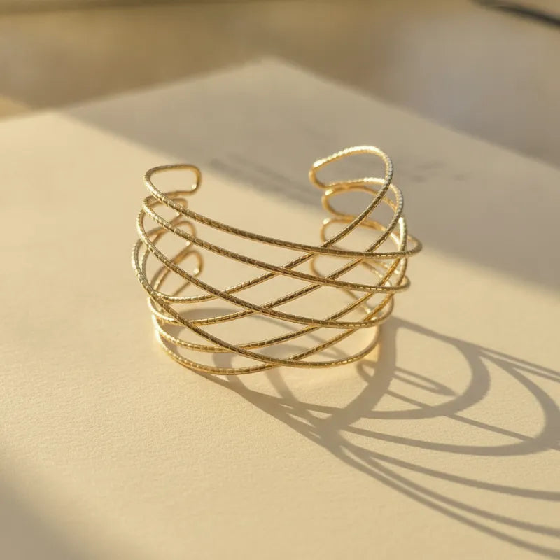 Multi-strand gold criss-cross cuff bracelet with a gold-toned woven wire design for elegant wear