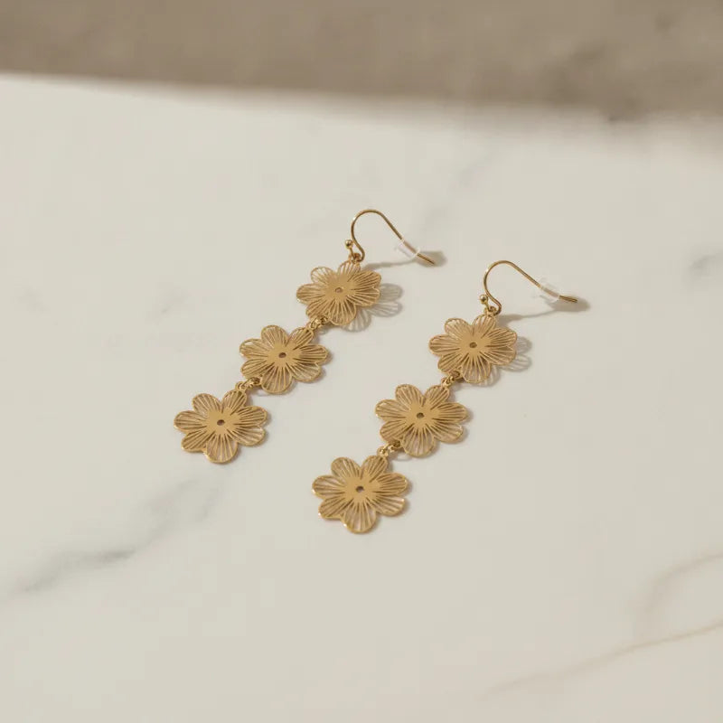 Three-tiered gold blossom statement dangle earrings with three intricately cut floral charms linked by delicate chains