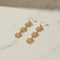 Three-tiered gold blossom statement dangle earrings with three intricately cut floral charms linked by delicate chains
