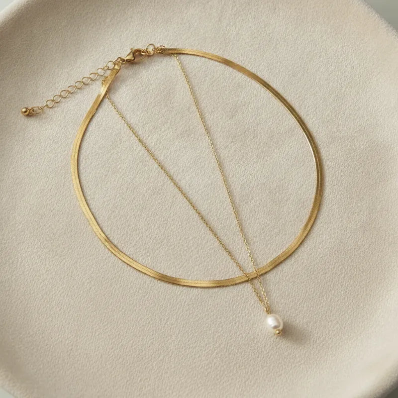 Gold-toned double snake chain necklace featuring a sleek thin snake chain with a single freshwater pearl pendant charm