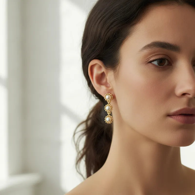 Gold-toned triple pearl dangle earrings with three cascading pearl beads in a delicate floral metal setting