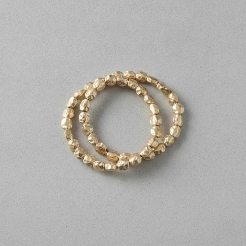 Gold-toned hammered bead stacking rings forming a hammered gold stretch bracelet stack for elegant layering