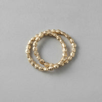 Gold-toned hammered bead stacking rings forming a hammered gold stretch bracelet stack for elegant layering