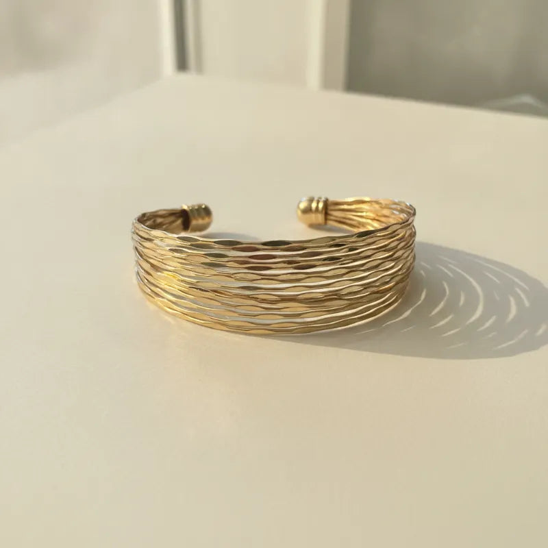 Gold-toned hammered metal cuff bracelet with layered textured design in the golden tide cuff collection