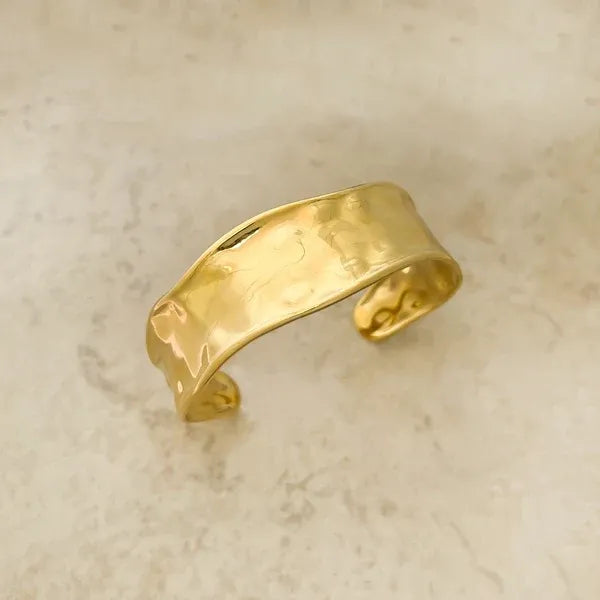 Gold-toned hammered surface water resistant metal cuff bracelet with a smooth slightly curved design
