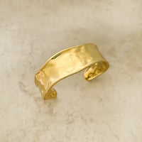 Gold-toned hammered surface water resistant metal cuff bracelet with a smooth slightly curved design
