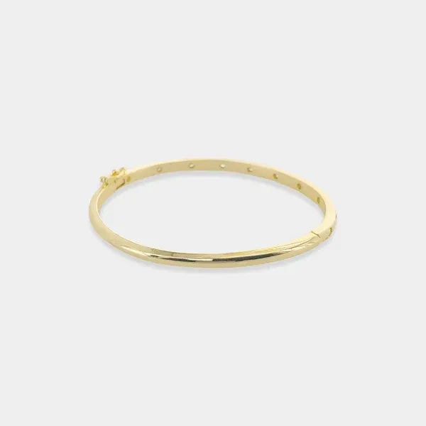 Thin polished cubic zirconia bangle in gold tone with hinged design and subtle dot accents along its length