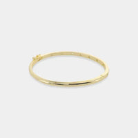 Thin polished cubic zirconia bangle in gold tone with hinged design and subtle dot accents along its length