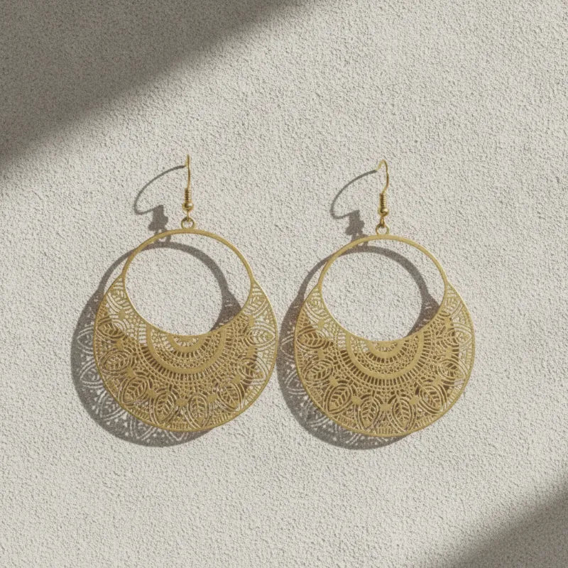Gold-toned filigree metal drop earrings with intricate boho mandala-style cutout patterns for elegant wear