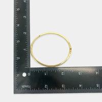 Gold-toned hoop earring with a polished cubic zirconia finish and clasp mechanism complementing cubic zirconia bangle