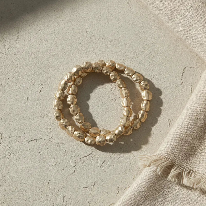 Gold-toned hammered gold stretch bracelet featuring irregular textured beads in a stylish bracelet stack design