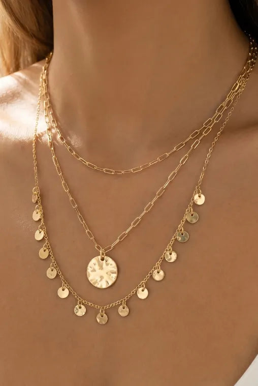 Gold-toned triple layer hammered coin necklace with central hammered disc pendant and dangling circular charms on delicate chains