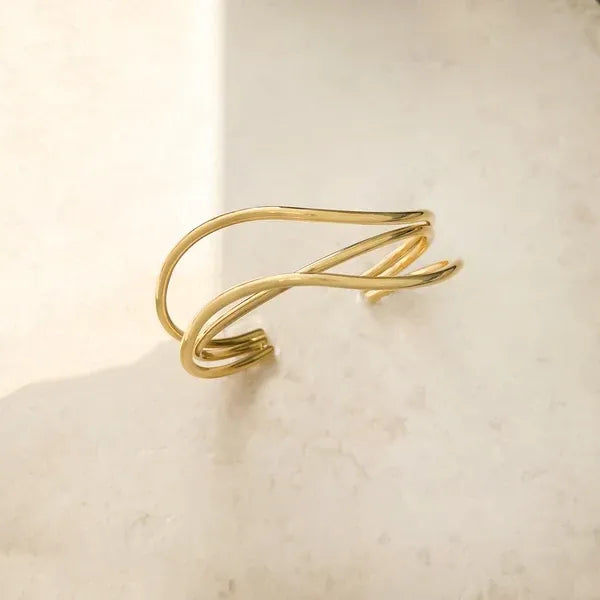 Gold-toned minimalist cuff bracelet featuring a water resistant three curved bands design in sleek intertwined wire