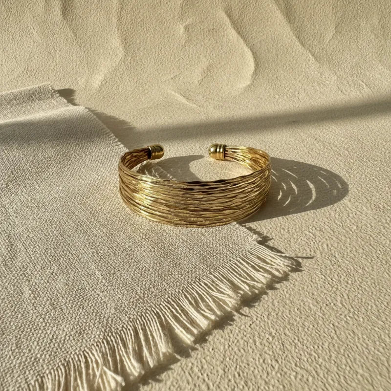 Gold-toned multi-strand woven cuff bracelet with textured braided design and polished spherical clasps golden tide cuff