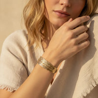 Gold-toned multi-strand woven bracelet with a textured braided design from the golden tide cuff collection