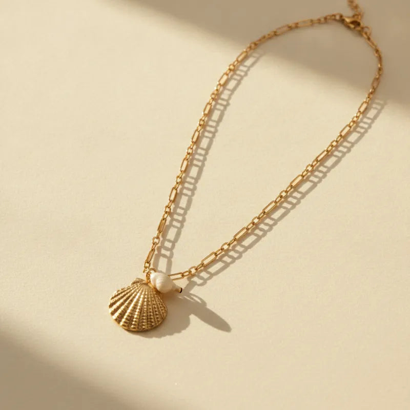 Gold-toned necklace with a detailed marine shell pendant and a small pearl for elegant everyday wear