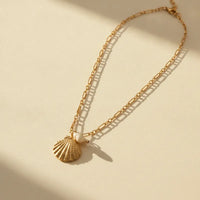 Gold-toned necklace with a detailed marine shell pendant and a small pearl for elegant everyday wear