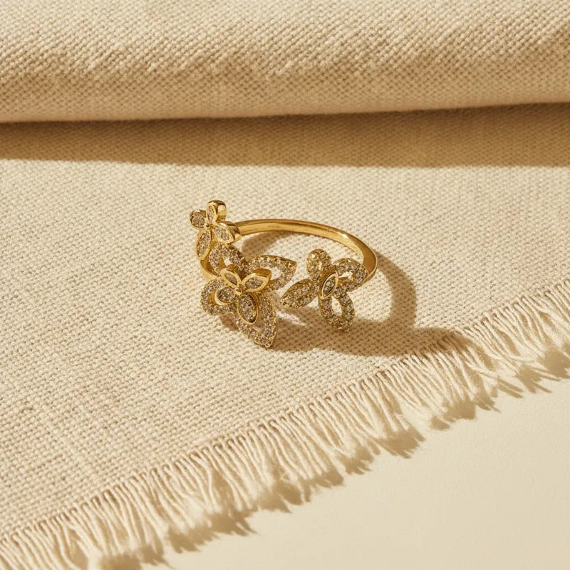 Gold-toned open bypass statement ring with three floral motifs and sparkling clear stones in butterfly open bypass design