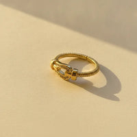 Gold plated cable band statement ring with twisted design and buckle centerpiece adorned with sparkling stones