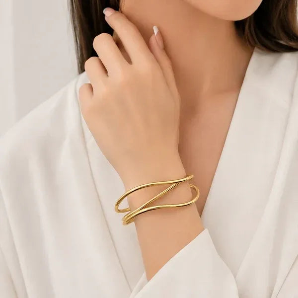 Gold-toned water resistant three curved bands cuff bangle with sleek intersecting design worn on the wrist