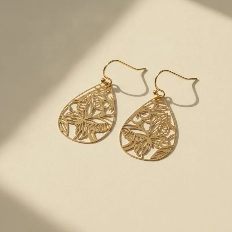 Delicate gold lacecut teardrop earrings featuring intricate butterfly filigree and leaf cutout designs in gold tone
