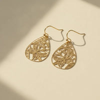 Delicate gold lacecut teardrop earrings featuring intricate butterfly filigree and leaf cutout designs in gold tone