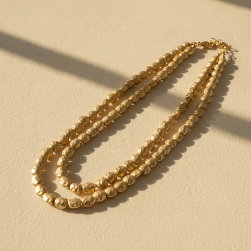 Double-strand matte gold hammered bead statement necklace with textured layered design in gold tone