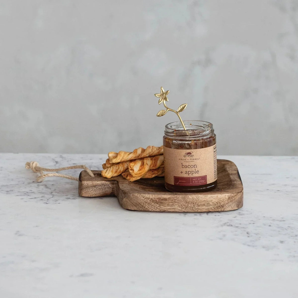 Hand-carved mango wood serving board with golden star utensil and bacon apple jam jar