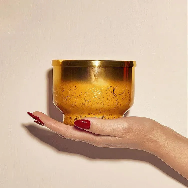 A golden textured bowl with a reflective metallic rim held in hand for the pumpkin dulce glimmer inverted candle