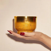 A golden textured bowl with a reflective metallic rim held in hand for the pumpkin dulce glimmer inverted candle