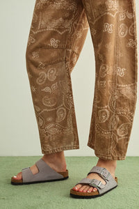 Gray suede birkenstock sandals with two silver buckle straps and cork footbed paired with paisley print washed pants