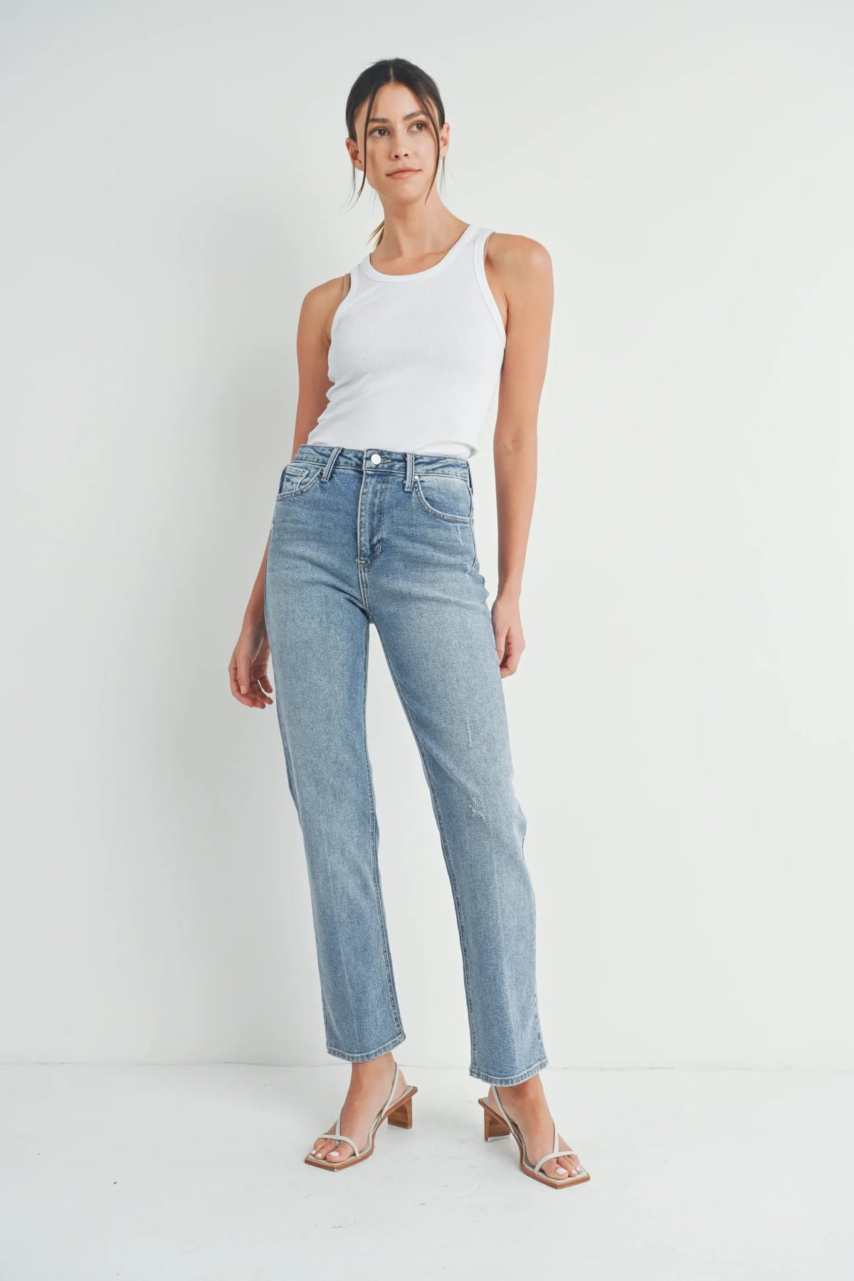 High-waisted full length straight denim jean in light blue wash with subtle distressing and classic five-pocket design