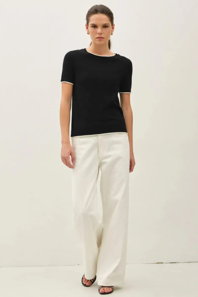 Black knit essential short sleeve sweater top with white trim along neckline and sleeve hems layered look essential short sleeve