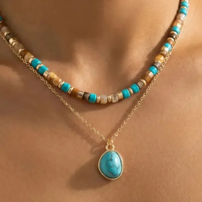 Layered turquoise stone drop bead necklace featuring turquoise and gold-toned beads with matching oval pendant