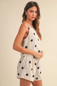 A light beige polka dot linen sleeveless romper with thin straps featuring a dot linen sleeveless design