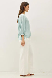 A light blue loose-fitting blouse with a notched y-neck volume sleeve and puffed sleeve design