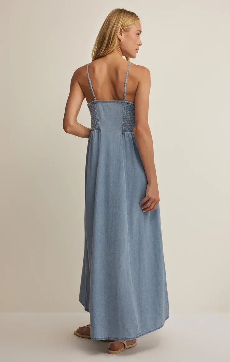 A light blue angel eyes chambray midi dress with thin straps and a smocked waistband in chambray fabric