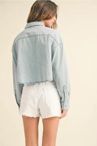Light blue short body denim shirt with classic collar and buttoned cuffs in a cropped body denim shirt style